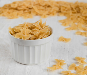 Dry uncooked farfalle pasta in a bow on a white background. Side view.