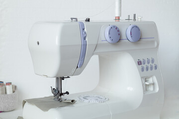 White modern sewing machine on a white table. Tailor's workplace.