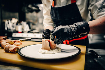 Chef's hands in gloves cooking fried thin pancakes crepe stuffed potato with herring fish on kitchen