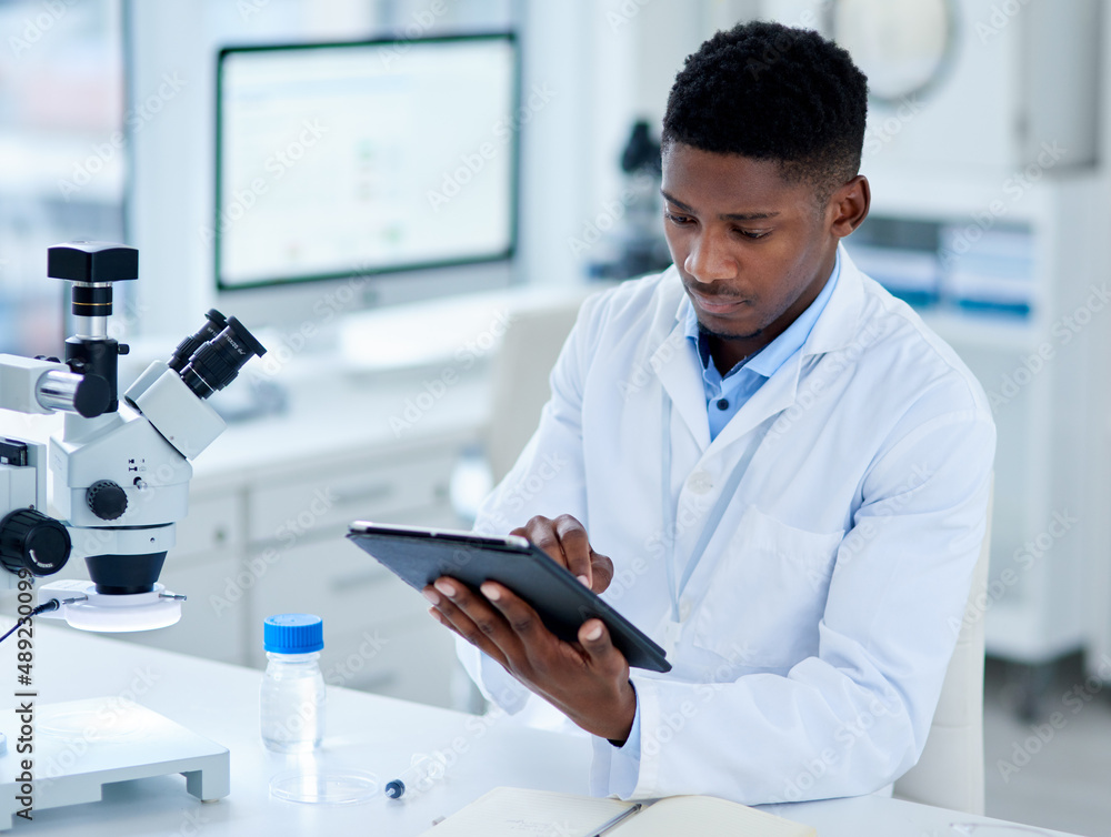 Poster what is he up to today. cropped shot of a focused young male scientist browsing on a digital tablet 