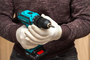 Man, master holds a cordless screwdriver to tighten the screws