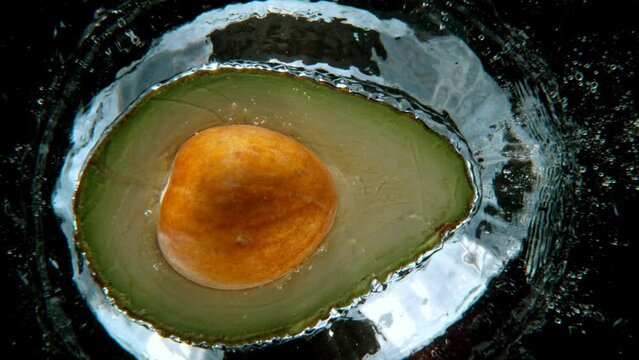 Fresh avocado falling into water, super slow motion filmed on high speed cinematic camera at 1000 fps.