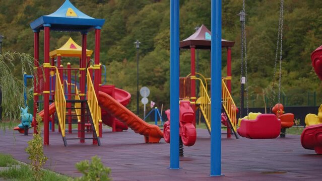 Wet empty children's playground in a city park on a rainy day. Slow motion. 