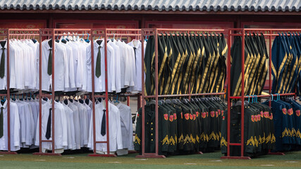 Rote Kleiderstangen mit schwarzen sowie weißen chinesischen Militäruniformen, gereinigt und...