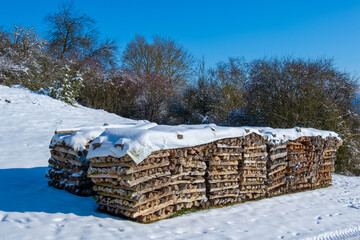 Holzwirtschaft: Gestapeltes Brennholz / Meterholz (Holzlager im Winter bei Schnee) -...