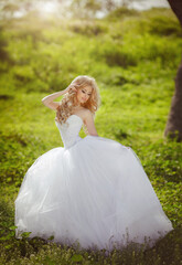 Fototapeta na wymiar A beautiful blonde bride with a cool make-up in a wedding dress holds a bridal bouquet against the backdrop of a beautiful, green nature. Husband and wife, happy together, just married, newlyweds.