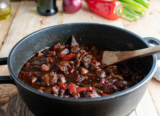 Spicy meat dish with stewed chicken breast, chili, onions and red bell peppers in a pot