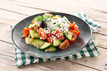 Traditional Bulgarian shopska salad with tomato,cucumber and bulgarian sirene cheese on wooden table