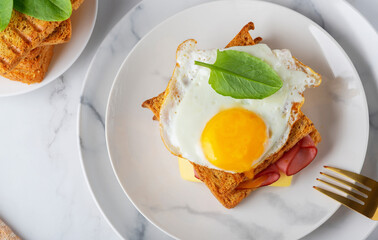 Sandwich with a fried egg, bacon, cheese and spinach