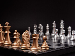 One chess piece stands against a full set of chess pieces. The concept of strategy, planning and decision-making