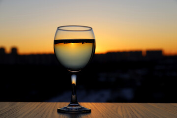 Glass with white wine on background of city at sunset. Concept of celebration, romantic travel