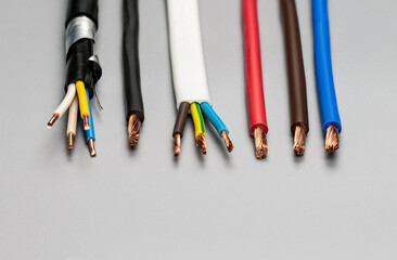 Different types of copper wires with insulation on a gray background