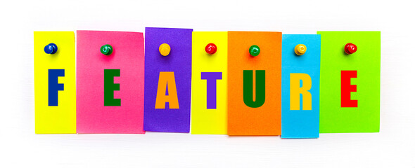 On a white background, buttons are used to fix bright multi-colored strips of paper with the text FEATURE
