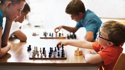 Chess whiz. Young boy wearing spectacles and playing chess with an older child.