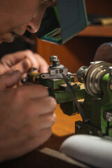 Jeweler with head magnifying glasses cuts a part on the machine