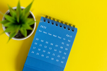 Desktop calendar for April 2022 on a yellow background.