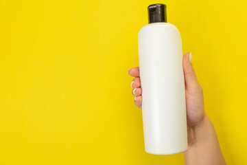 Cleaner's hand holding a  chemical spray bottle. Empty space for text or logo on a yellow background. Early spring or regular cleaning. Cleaning and cleaning concept. flat lay