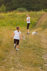 mom, daughter and dogs run in nature