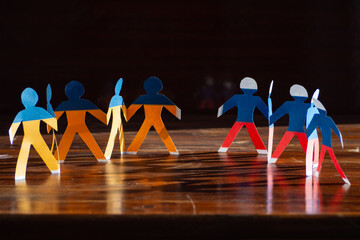 Paper men painted in the colors of the Ukrainian and Russian flags stand opposite each other. A...