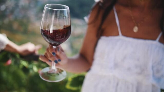 Hand of young woman shakes glass of red wine 