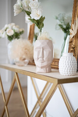 Flowers in vases on the coffee table against the background of a mirror. Modern interior items.