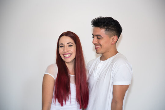 embracing couple, smiling, with neutral background, dark-haired boy, red-haired girl