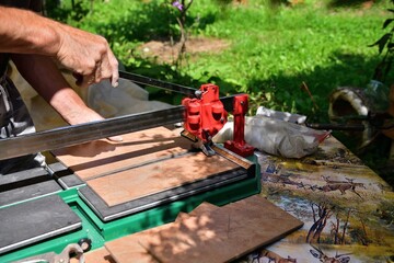 The mason cuts the tile by hand using a cutter