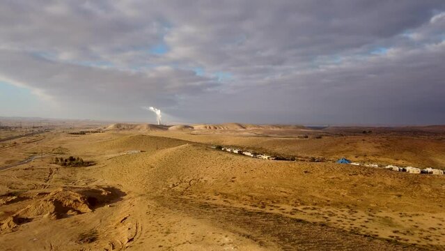Flying to the solar power station Ashalim over the settlement Sheizaf in Negev desert under thunderclouds before rain