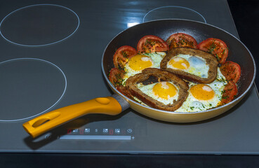 Pan with fried eggs and tomato slices on induction stove. Sweden. 