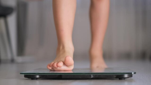 Child measuring weight. Weight control concept with centimeter in focus and blurred kid's feet on digital scale.