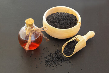 glass bottle of black cumin seeds essential oil , Nigella Sativa in spoon and bowl on wooden rustic...