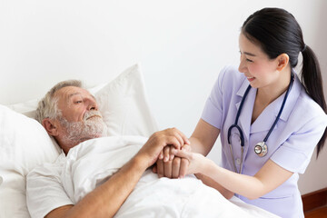 Fototapeta premium Nurse cares for elderly man lying in bed