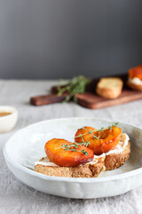 Summer Breakfast - toast (sandwich, bruschetta) with grilled peaches, cream cheese (ricotta, mascarpone), thyme and honey on beige linen tablecloth. Selective focus - 489242606