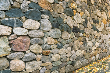 Background of stones. A wall of multicolored stones. The masonry is made of untreated stones. A wall of large stones.