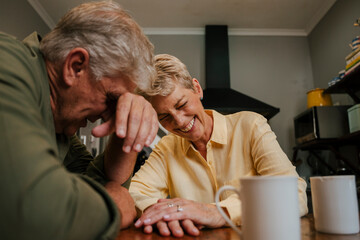 Happy caucasian senior couple laughing together at morning tea