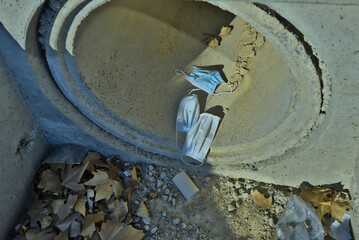 dry pipe with discarded face masks, leaves and plastics