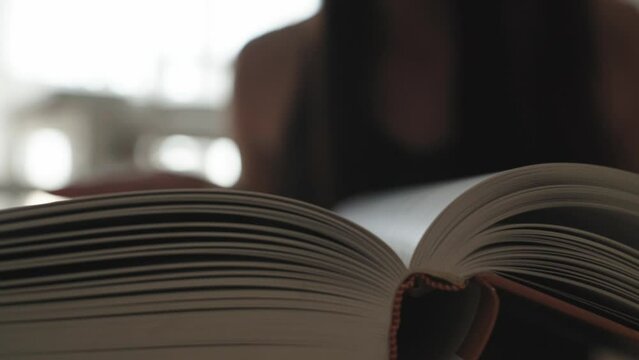 young Spanish woman turning the pages of a book looking for a specific content and reading the text