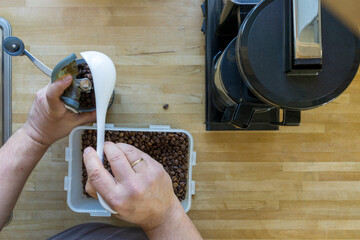 Man grinds coffee beans with a traditional coffee grinder using a hand-crank to make the coffee...
