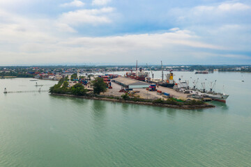 Fototapeta premium Aerial view of cargo ship in the harbor at beautiful sunset