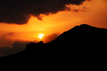 Beautiful quiet sunset with orange skies and backlit mountains. Sun peeking through the mountains. Somoto Canyon, Madriz, Nicaragua.