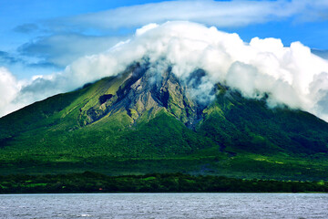 Breathtaking view of volcano on a sunny morning. Volcano on the shores of a lake. Clouds at the top. Mountain reliefs. Lake Cocibolca. Concepcion Volcano, Ometepe Island. Nicaragua, Central America.