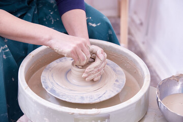 hands of a ceramist make dishes on a potter's wheel.