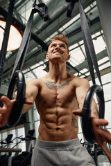 Fototapeta na wymiar Muscle-up exercise young man doing intense cross fit workout at the gym on gymnastic rings.