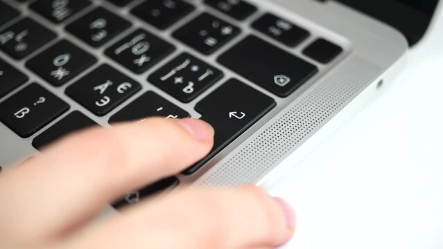 Hand pressing enter key several times on modern laptop keyboard close-up slow motion video