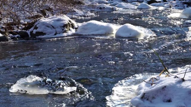 Bergbach im Winter mit Eis und Schnee - Bachlauf mit Steine und klarem Wasser