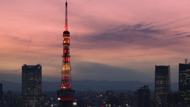 tokyo, japan - february 22 2022: Slide down video of a sunset cityscape depicting the Tokyo tower and Roppongi Hills skyscrapers in Shibadaimon district at golden hour.