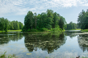Fototapeta premium The view of the Charlotte Lieven island mirroring in the lake in the middle of the Pink Pavilion Pond in Pavlovsk Park, St Petersburg, Russia