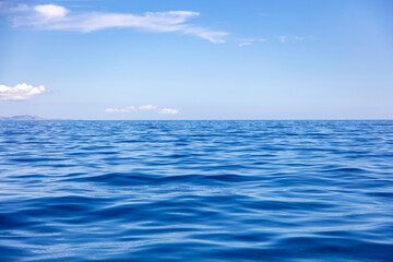 Obraz premium Ocean sea water surface deep blue, calm with ripple, small cloud on blue sky background,