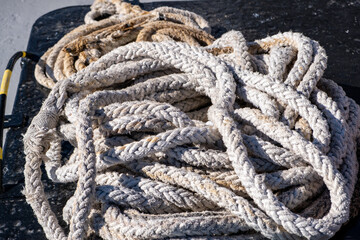 Fototapeta na wymiar Boat rope old worn out, rope for ship mooring in the port, overhead closeup view
