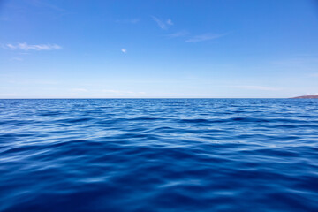 Fototapeta na wymiar Ocean sea water surface deep blue, calm with ripple, small cloud on blue sky background,